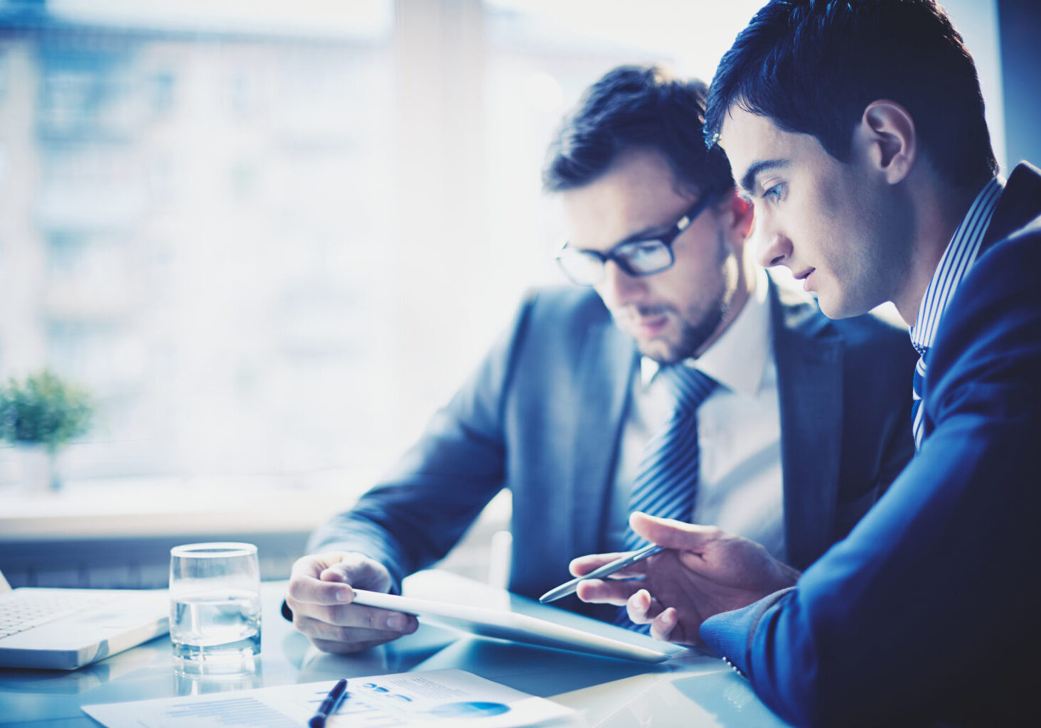 Image of young businessman pointing at touchpad while explaining his idea to colleague at meeting